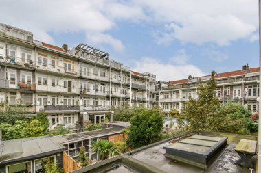Yeşillik, balkon ve mimarinin yer aldığı şehir avlusunun manzarası. Binanın çevresi yemyeşil bir bahçe, rahatlamak için mükemmel..