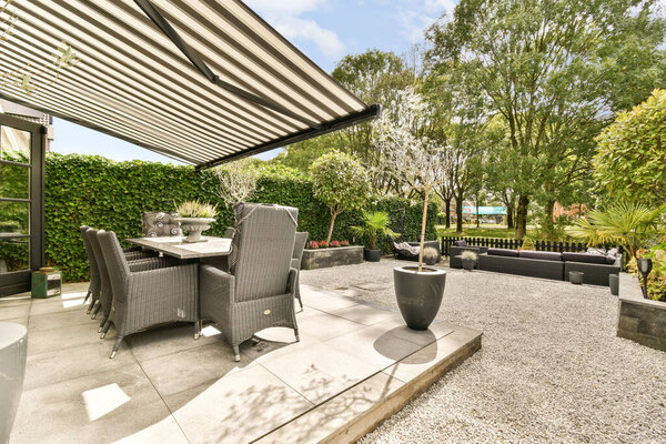A stylish outdoor patio featuring sleek furniture, greenery, and a peaceful ambiance, perfect for relaxation and social gatherings.