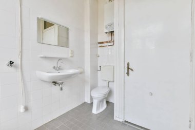 Beyaz fayanslı duvarları olan eski, parlak bir tuvalet odası.