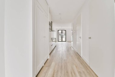 Beyaz duvarları olan uzun bir koridorun içinde.