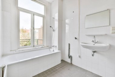 Beyaz fayanslı duvarları olan eski, parlak bir banyo.