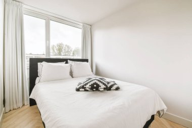 Beyaz siyah yastıklı, çift kişilik yataklı basit bir yatak odası.