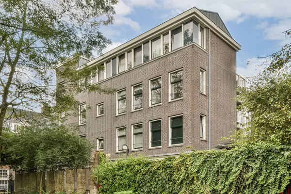 Görüntü, üssü çevreleyen karmaşık tasarım ve yeşillikle modern bir tuğla bina sergiliyor ve çağdaş kent mimarisini vurguluyor..