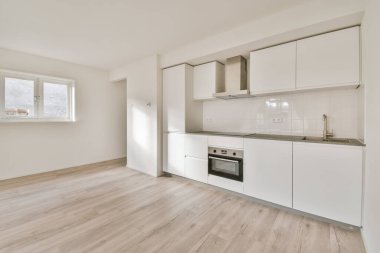 Boş bir odada beyaz dolapları olan modern bir mutfak.