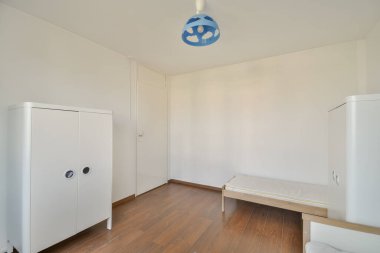 Parlak, minimalist çocukların yatak odası. Hafif ahşap döşemesi, yatak çerçevesi ve eşsiz tavan lambası olan basit bir tasarım..