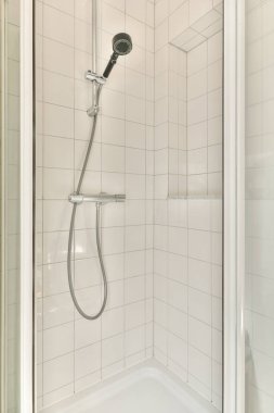 Beyaz fayans duvarları ve modern el yapımı duş başlığı olan gösterişli ve minimalist bir duş kabini. Çağdaş tuvaletler için mükemmel..