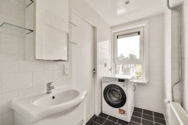 Çağdaş banyo bir çamaşır makinesi, parlak lavabo ve parlak, cam elementli temiz estetik içerir..