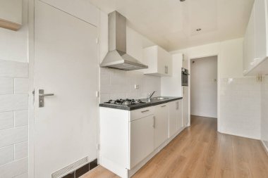 Temiz çizgileri, beyaz dolapları ve ahşap döşemeleri olan, çağdaş yaşam alanları için mükemmel minimalist tasarımı olan gösterişli, modern bir mutfak..