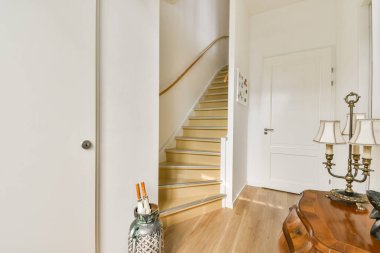 Pürüzsüz ahşap basamakları ve zarif ışıklandırmasıyla koridorun estetiğini geliştiren güzel tasarlanmış modern bir merdiven..