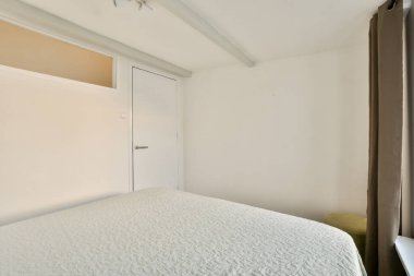 Pencereden süzülen minimalist dekoru ve geniş doğal ışığı olan temiz bir tasarımı sergileyen el değmemiş modern bir yatak odası..