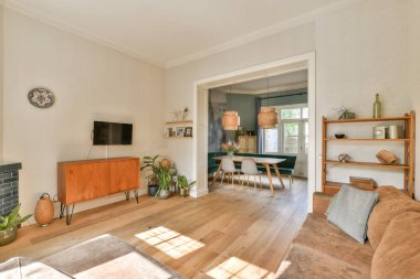 Ahşap döşeme, minimalist mobilyalar ve konforu ve estetiği artıran zevkli dekorların yer aldığı modern bir oturma odası..
