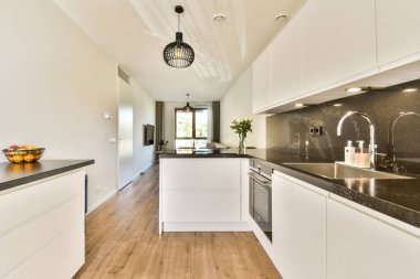 Beyaz dolapları, parlak tezgahları ve doğal ışıklandırması olan çağdaş tasarımı olan şık bir mutfak. Parlak ve davetkar bir atmosfer yaratıyor..