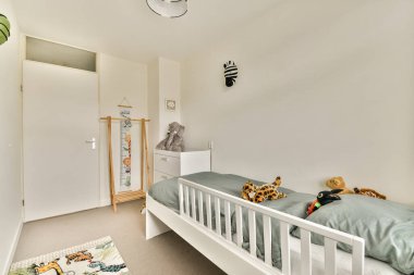 Beyaz bir yatak odası, eğlenceli oyuncaklar ve neşeli duvar resimleri olan parlak ve davetkar bir çocuk odası. Rahat ve eğlenceli bir atmosfer için mükemmel..