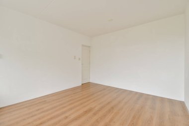 Açık ahşap zemin ve beyaz duvarların yer aldığı geniş, boş bir oda, çeşitli amaçlar için parlak ve minimalist bir atmosfer yaratıyor..