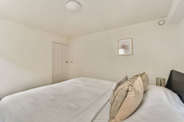 Bu huzurlu yatak odası, minimalist bir tasarım, rahat bir yatak ve rahat dekorasyon öğeleri içeriyor. Rahatlamak ve gevşemek için huzurlu bir alan yaratıyor..