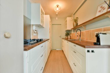 Beyaz dolaplı, ahşap tezgahlı, şık ve modern mutfak vitrinli bir minimalist tasarım, ve modern aydınlatma armatürü, şık bir yemek alanı yaratıyor..