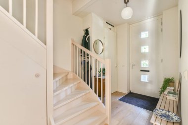 Bir merdiven, şık bir dekor ve doğal ışık içeren davetkar modern bir giriş. Bu tasarım rahat bir uzayda basitlik ve işlevselliği vurgular..