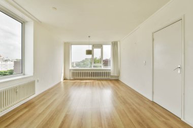 Geniş pencereli ve parlak ahşap döşemeli parlak ve dağınık bir oda. Modern yaşam ya da çalışma alanı için idealdir, basitlik ve zarafet yayar.