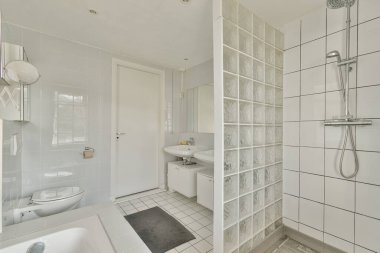 Çağdaş fayanslar, duş ünitesi ve temiz estetik için minimalist eşyalar içeren gösterişli ve modern bir banyo..