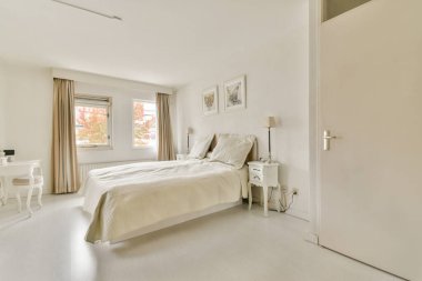 Yumuşak nötr renkler, doğal ışık ve minimalist dekor içeren sakin ve zarif tasarlanmış bir yatak odası, rahatlama ve rahatlama için mükemmel..