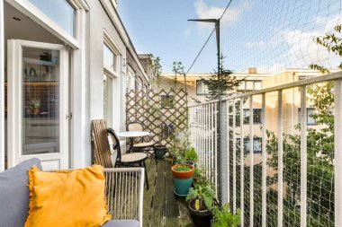 Rahat koltuklar, saksı bitkileri ve rahatlamak ve keyif almak için mükemmel binalar ve ağaçlar manzaralı güzel düzenlenmiş bir balkon..