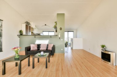Doğal ışığı, şık mobilyaları ve dekoratif unsurları olan minimalist bir estetiğe sahip geniş ve modern bir oturma odası. Tasarım basitliği ve rahatlığı vurgular..