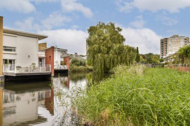 Bereketli yeşillikler ve sakin bir atmosferle çevrili sakin bir su yolu boyunca büyüleyici konut binaları. Barışçıl yaşam ve doğa severler için ideal..