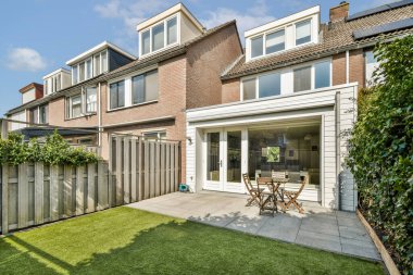 Yeşillik ve konut mimarisi ile çevrili, rahatlama ve rahatlama için mükemmel, modern bir terası olan güzel tasarlanmış bir arka bahçe..