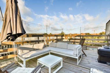 Modern oturma düzenleri, beyaz bir masa ve rahatlama ve toplanma için mükemmel davetkar bir atmosfer içeren şık bir açık hava terası..