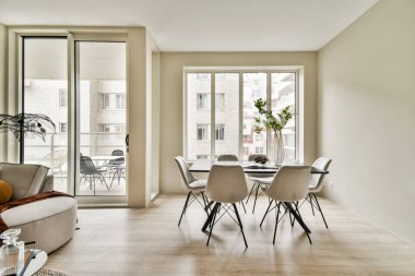 Büyük pencereler, zarif mobilyalar ve biraz yeşillik içeren şık bir yaşam alanı, sıcak ve davetkar bir atmosfer yaratıyor..