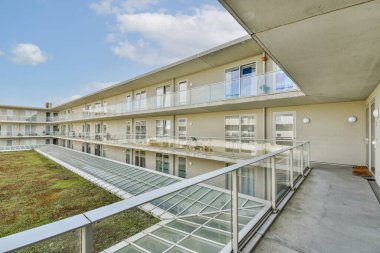 Çağdaş bir bina tasarımında yeşil ve balkonlu geniş bir iç avlu, modern yaşam estetiği ve çevre entegrasyonu sergileniyor..