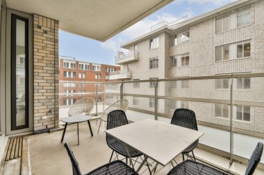 Beton zemini, modern mobilyaları ve bitişik binaları olan minimalist bir tasarımı olan şık bir balkon. Rahatlamak için mükemmel bir manzara..