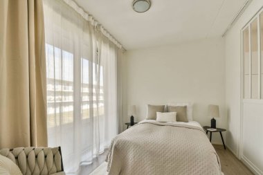 Yumuşak çarşafların, saf perdelerin arasından süzülen doğal ışığın ve rahatlatıcı bir atmosfer için basit bir renk paletinin olduğu sakin ve minimalist bir yatak odası..