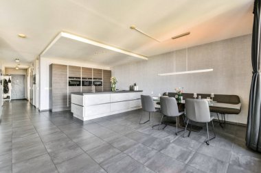 Pürüzsüz ve çağdaş mutfak alanı koyu renk dolaplı minimalist bir tasarım ve toplanma için mükemmel bir yemek masası..