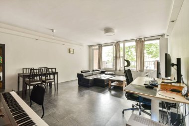Rahat bir kanepe, yemek masası ve bilgisayarlı özel çalışma alanı olan geniş pencereli geniş bir modern oturma odası..