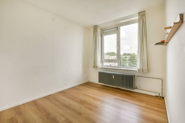 Pürüzsüz ahşap döşemeleri, doğal ışığa izin veren geniş bir penceresi ve modern yaşam için mükemmel minimum mobilyaları olan dağınık bir iç mekan..