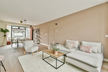 Rahat bir oturma odası, parlak mobilyalar ve nötr renk tonları olan modern bir oturma odası. Rahatlamak için sıcak ve davetkar bir atmosfer yaratıyor..