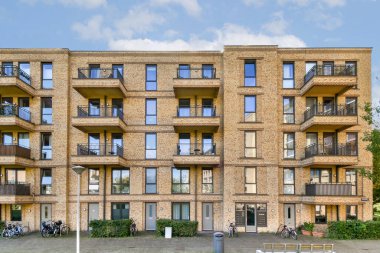 Modern bir apartman manzarası, çok sayıda balkon ve geniş pencereleri açık gökyüzüne karşı sergiliyor ve çağdaş mimariyi vurguluyor..