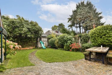 Canlı bitkiler, bir kaydırak ve bir dolambaçlı yol içeren sakin bir bahçe, ağaçlar ve yemyeşil, rahatlama ve oyun için mükemmel.