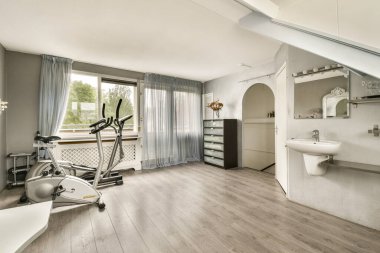 Spor aletleri, doğal ışık ve parlak tasarım unsurlarının yer aldığı çağdaş bir spor salonu, fitness aktiviteleri için davetkar bir atmosfer yaratıyor..