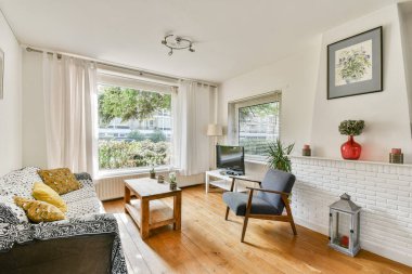 Bu parlak ve havadar oturma odasında geniş pencereler, şık mobilyalar ve rahatlamak ve sosyalleşmek için mükemmel bir karşılama atmosferi var..