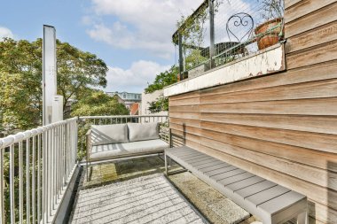 Yeşilliklerle çevrili çağdaş oturaklı şık bir balkon. Rahatlamak ve temiz havanın tadını çıkarmak için ideal. Kentsel yaşam alanları için mükemmel.