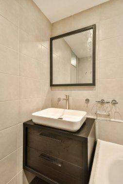 Zarif ve çağdaş bir banyo şık eşyalar ve minimalist bir tasarım. Yer, günlük kullanım için bir ayna ve uygun bir lavabo alanı içeriyor..
