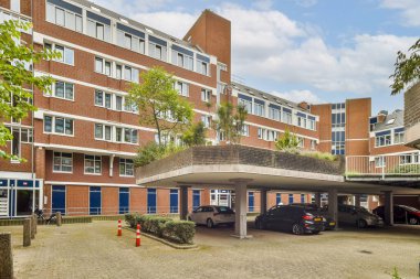 Çağdaş bir konut binasında birden fazla pencere, yeşillik ve bir yeraltı otoparkı bulunur. Tasarımda modern mimari ve kentsel yaşam sergileniyor.