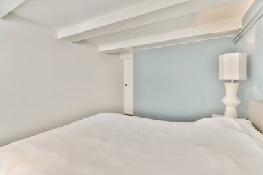 Yumuşak, nötr renk paleti, basit mobilya tasarımı ve parlak doğal ışık içeren sakin ve minimalist bir yatak odası rahatlatıcı bir atmosfer yaratıyor..