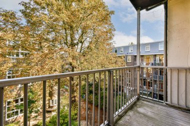 Canlı sonbahar yapraklarının sergilendiği bir balkondan güzel bir manzara ve sakin bir mahalle manzarası doğadaki geçişin özünü yansıtıyor..