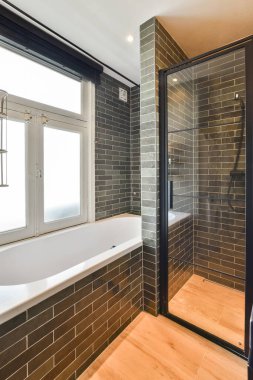 Şık bir banyo, cam bir duş, şık bir küvet, ve modern fayans tasarımı, zarif ve geniş bir atmosfer yaratıyor..