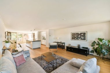 Çağdaş mobilyaların, yemyeşil yeşilliğin ve bol doğal ışığın bulunduğu geniş bir oturma odası huzurlu ve davetkar bir atmosfer yaratıyor..