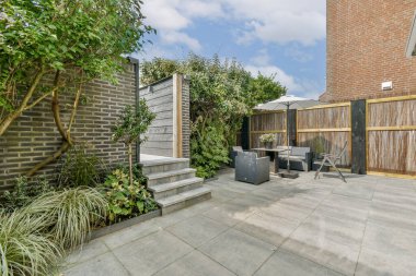 Çağdaş çitlerle çevrili taştan basamaklar, rahat koltuklar ve yemyeşil bir bahçe. Rahatlamak ve eğlenmek için mükemmel..