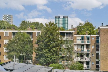Yeşillik ve modern mimari ile çevrili kentsel apartman manzarası, doğa ve kentsel yaşamın bir karışımını sergiliyor..
